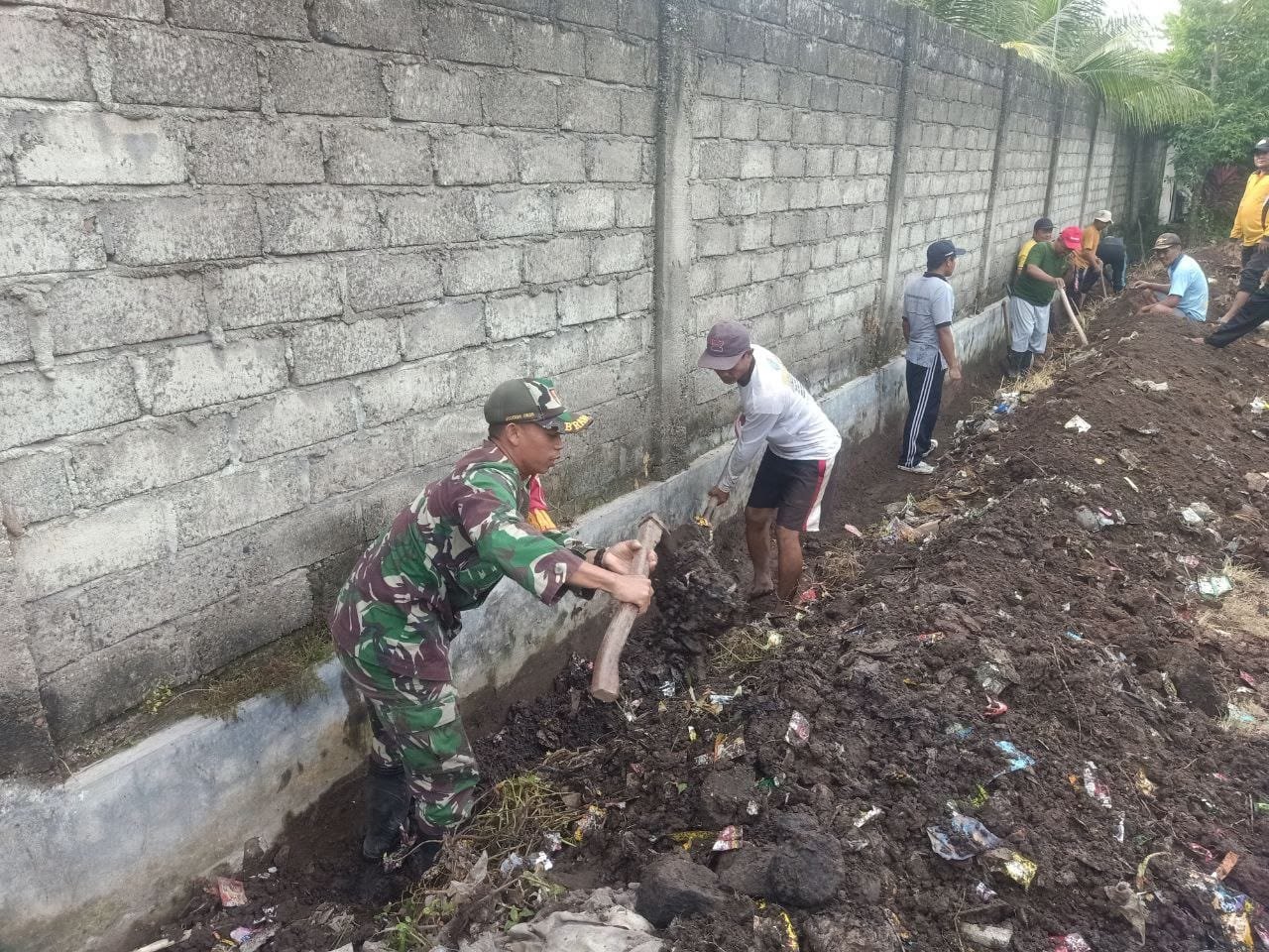 Wujudkan Lingkungan Sehat, Babinsa Koramil Rogojampi Ajak Warga Gotong Royong Membersihkan Jalan Desa